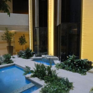 Three gold acrylic water features, with blue pools and indoor planters and pots to create a biophilic environment in this elevator lobby.